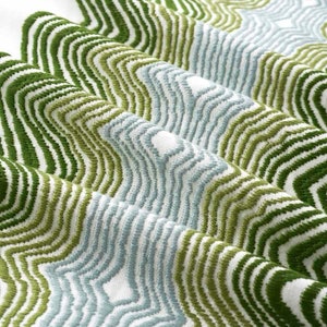 May include: Close-up of a white fabric with a wavy pattern in shades of green and blue.