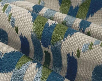 May include: A woven fabric featuring a textured off-white base with an abstract pattern of embroidered brushstroke shapes in shades of deep navy blue, medium blue, light blue, and olive green, arranged in a repeating vertical orientation.