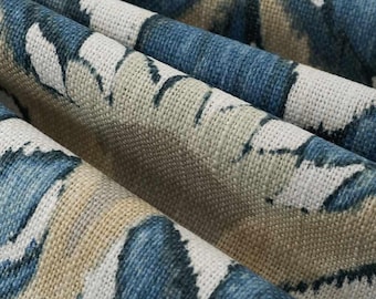 May include: A woven fabric featuring a repeating pattern of deep blue and beige abstract shapes. The material has a visible, coarse-textured weave with distinct folds that create shadows and highlights across the surface of the textile.