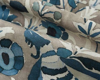 May include: A woven fabric featuring a repeating floral pattern in shades of deep navy blue, medium blue, and muted teal against a light beige background. The material displays a visible textured weave with soft folds creating depth and shadows.