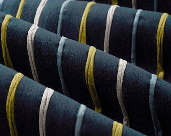May include: A dark blue fabric featuring a series of vertical stripes in alternating colors of light blue, off-white, and olive green. The material has a soft, textured surface with raised, corded lines running parallel across the folded textile.