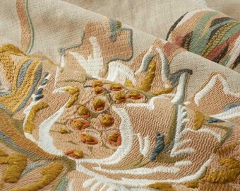 May include: A beige linen fabric featuring intricate floral embroidery in shades of mustard yellow, sage green, terracotta, and white. The design includes raised, textured stitching and detailed botanical patterns across the surface.
