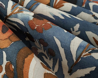 May include: A woven fabric featuring a dense floral pattern with deep blue, burnt orange, and cream-colored botanical motifs. The material displays a visible textured weave and is arranged in soft, cascading folds that highlight the intricate design.