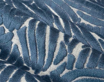 Op de afbeelding: Een stof met een diepblauwe fluwelen textuur en een verhoogd, herhalend bladvormig patroon. Het ontwerp bestaat uit zachte, pluche blauwe vormen tegen een lichtgrijze, geweven achtergrond, wat zorgt voor een duidelijk contrast in textuur.