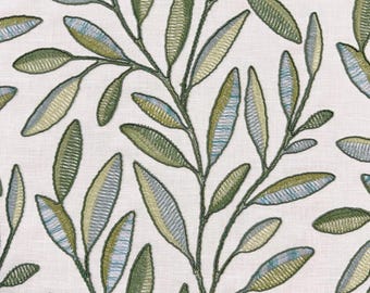 May include: A white fabric featuring an embroidered botanical pattern of trailing leafy branches. The leaves are stitched in varying shades of olive green, sage, and soft blue, with dark green thread outlining each individual leaf shape.