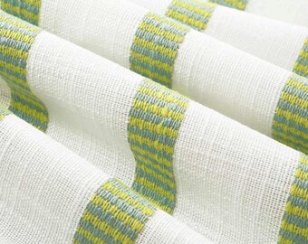 May include: Close-up of white fabric with green and blue striped pattern. The fabric is woven and has a textured surface.