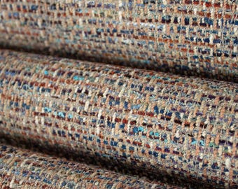 May include: A tightly woven fabric featuring a multi-colored textured pattern. The material displays a complex blend of threads in shades of blue, rust orange, cream, and dark purple, creating a dense, tactile surface with a visible grid-like weave.