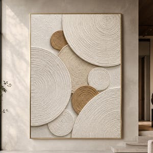 Peut inclure: Une œuvre d'art murale rectangulaire composée de plusieurs cercles superposés présentant un motif texturé de cercles concentriques. L'ensemble utilise une palette de couleurs neutres dans des tons crème, beige et brun clair, encadré d'un fin cadre doré.