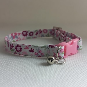 Può includere: Un collare floreale per gatti con fibbia in plastica rosa e campanella argentata. Il collare presenta uno sfondo bianco con motivi floreali rosa, viola e verdi. Il collare è largo circa 1,3 cm.