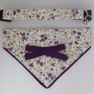 Può includere: Un collare e una bandana abbinati per gatto, con motivo floreale bianco e viola, con un fiocco viola. Il collare è dotato di un campanello.