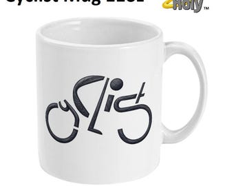 以下が含まれることがあります： 自転車を模した文字でCyclistと描かれた黒いグラフィックデザインの白い11オンスのセラミック製マグカップ。Cyclist Mug 11ozというテキストと、黄色い光輪が付いたHit It Holyのロゴが表示されています。
