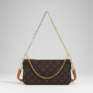 May include: A rectangular brown handbag featuring a repeating monogram pattern of the letter R and four-petaled floral motifs. The bag includes a gold-tone metal chain strap, a gold-tone zipper closure, and tan leather side attachments with metal clips.