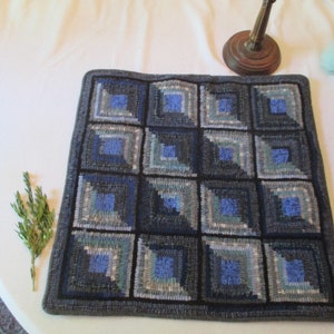 May include: A blue and gray wool rug with a log cabin pattern. The rug is made of hand-woven wool and has a fringed edge.