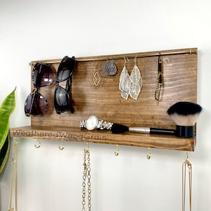 May include: A wooden wall-mounted organiser with a shelf and hooks for jewellery, sunglasses, and other accessories. The organiser has a weathered wood grain finish and the text "Weathered Wood Grain" is printed on the shelf.