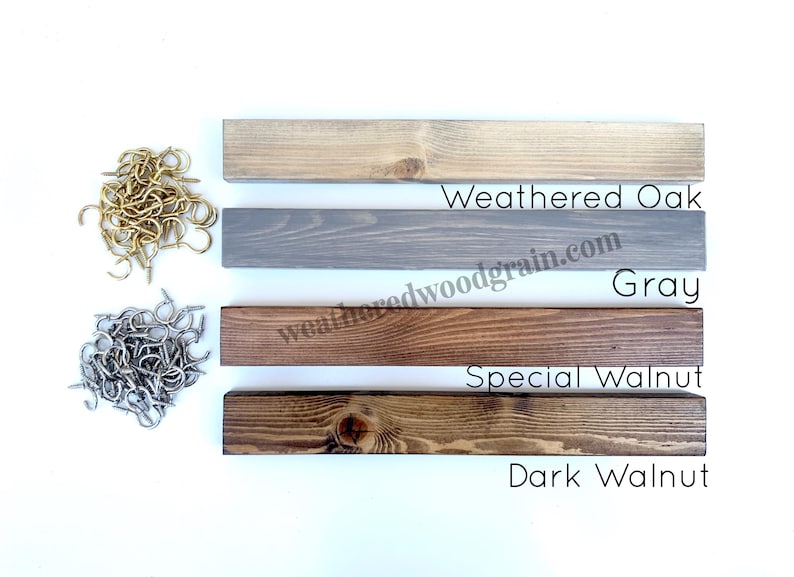 May include: Four rectangular wooden boards in Weathered Oak, Gray, Special Walnut, and Dark Walnut finishes, accompanied by two piles of metal screw hooks in gold and silver tones, with the text Weathered Oak, Gray, Special Walnut, and Dark Walnut.