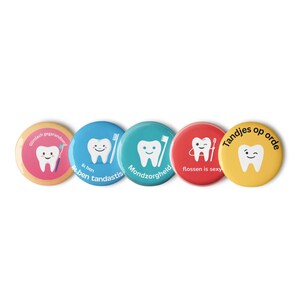 Op de afbeelding: Vijf ronde buttons met gekleurde achtergronden en witte illustraties van tanden. De buttons bevatten verschillende teksten, waaronder Glimlach gegarandeerd, Ik ben tandastis, Mondzorgheld, flossen is sexy en Tandjes op orde.