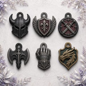 Może przedstawiać: Zestaw sześciu metalowych zawieszek z motywami fantasy, w tym hełm z rogami, skrzydlata tarcza z lilią, okrągły emblemat ze skrzyżowanymi mieczami, stylizowany topór, rękawica pancerna oraz głowa smoka na tarczy.