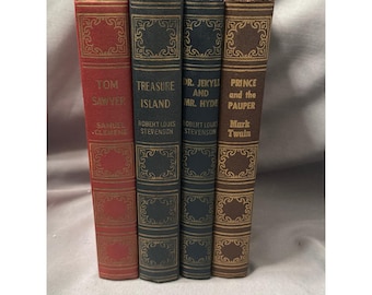 May include: A set of four hardcover books standing upright. The spines are red, dark blue, navy blue, and brown, each featuring gold embossed decorative borders and lettering. The titles include Tom Sawyer, Treasure Island, Dr. Jekyll and Mr. Hyde, and Prince and the Pauper, with their respective authors listed below.