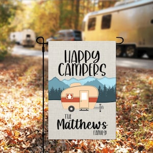 May include: A beige and red camper van with mountains and trees in the background. The text "Happy Campers" is at the top of the image. The text "The Matthews Family" is at the bottom of the image.