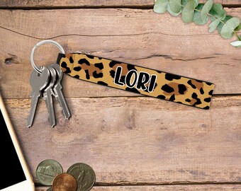 May include: A leopard print keychain with a silver key ring and the name "Lori" printed in white.