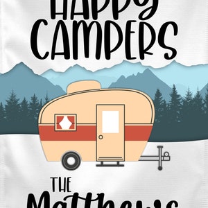 May include: A white canvas print with the text "Happy Campers" in black. Below the text is a cartoon image of a vintage camper in front of a mountain range. The text "The Matthews Family" is below the camper.