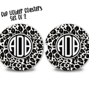May include: Set of two black and white leopard print car cup holder coasters with a black monogram "AOB" in the center of each coaster.