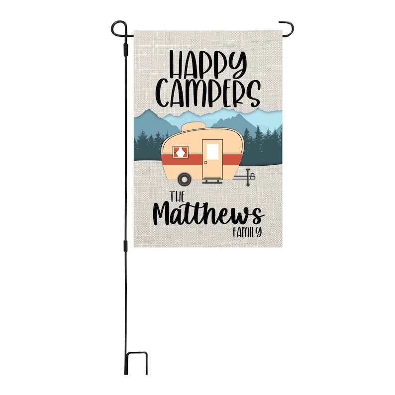 May include: A garden flag with a vintage camper illustration, mountains, and trees. The text reads "Happy Campers" and "The Matthews Family".