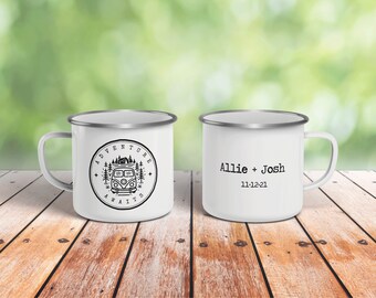 May include: Two white enamel mugs with silver rims. One mug has a black and white graphic of a vintage camper van with the text "Adventure Awaits". The other mug has the text "Allie + Josh 11-12-21".