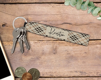 May include: A keychain with a plaid pattern in shades of brown, tan, and black. The keychain has a tag that reads "Kristen" in a cursive font. Several keys are attached to the silver keyring.
