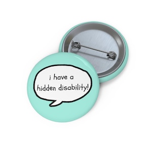 Può includere: Una spilla rotonda con sfondo verde menta chiaro. La parte anteriore presenta un fumetto bianco con bordo nero contenente il testo nero: i have a hidden disability! Il retro mostra un meccanismo a spilla in metallo argentato per l'aggancio.