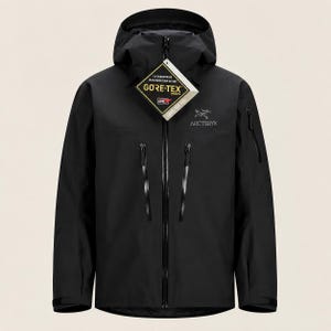 Op de afbeelding: Een zwarte jas met capuchon, voorzien van een volledige ritssluiting aan de voorzijde, twee verticale borstzakken met zwarte ritsen en een klein zakje met ritssluiting op de linkermouw. Het Arc'teryx-logo staat op de borst.