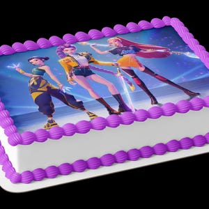 May include: A rectangular sheet cake with white frosting and a purple piped border. The top features an edible image of three animated characters in colorful outfits, with one holding a glowing sword and another holding a glowing staff on a blue background.