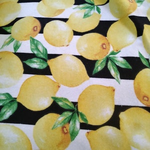 May include: Black and white striped fabric with a repeating pattern of yellow lemons. The lemons are painted in a watercolor style with green leaves.
