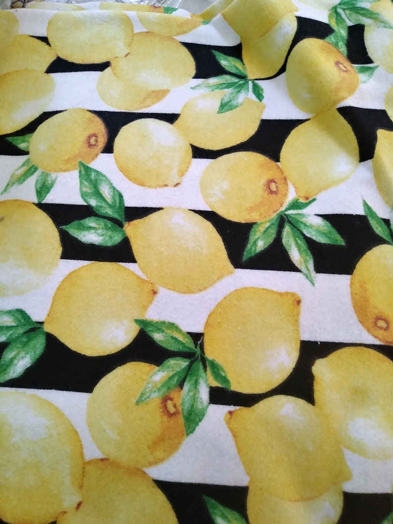May include: Black and white striped fabric with a repeating pattern of yellow lemons. The lemons are painted in a watercolor style with green leaves.