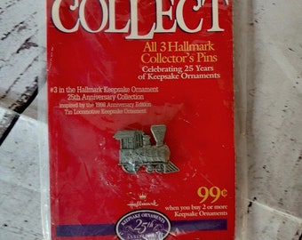 Peut inclure: Une figurine de train en argent de la collection Hallmark Keepsake Ornaments. La figurine est emballée sur une carte rouge avec le texte "COLLECT All 3 Hallmark Collector's Pins Celebrating 25 Years of Keepsake Ornaments #3 in the Hallmark Keepsake Ornament 25th Anniversary Collection inspired by the 1998 Anniversary Edition Tin Locomotive Keepsake Ornament 99¢ when you buy 2 or more Keepsake Ornaments Hallmark Keepsake Ornaments 25th Anniversary 1973-1993 Hallmark Cards, Inc."