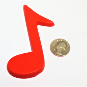 May include: A bright red plastic musical note, approximately the size of a UK 20 pence coin.