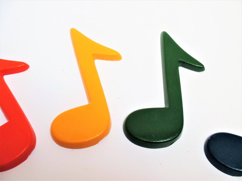 May include: Four colourful music note shapes made of wood. The notes are red, orange, green, and blue.