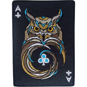 May include: A rectangular black embroidered patch featuring an ace of clubs playing card design. The center displays a stylized owl with brown, tan, and bright blue feathers, yellow eyes, and a white club symbol integrated into its chest.