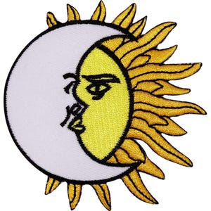 Peut inclure: Un écusson brodé présentant un design à double face. Un côté est un croissant de lune blanc, et l'autre est un soleil jaune vif avec des rayons dorés. Le visage central présente des contours noirs brodés pour l'œil, le sourcil et les lèvres.