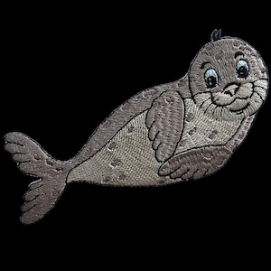 May include: An embroidered patch featuring a cartoon seal with light brown fur, darker brown spots, and a smiling expression. The seal is depicted in a swimming position with its flippers tucked against its body and a tail fin extended outwards.