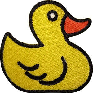 Puede incluir: Un parche bordado termoadhesivo con forma de patito de goma. El pato es de color amarillo brillante con un pico naranja vibrante, un ojo negro con el centro blanco y gruesas costuras negras que perfilan toda la forma y el detalle del ala lateral.
