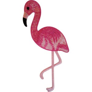 Puede incluir: Un parche bordado termoadhesivo con forma de flamenco de pie. El ave presenta detalles en hilo rosa vibrante, un cuello largo y curvado, y un pico con la punta negra. Las patas están representadas en un tono rosa más claro, visto de perfil.