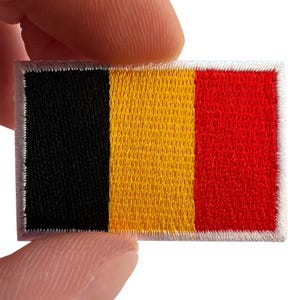 Op de afbeelding: Een rechthoekige geborduurde patch met de nationale vlag van België met verticale banen in zwart, geel en rood. De patch heeft een witte gestikte rand rondom de gehele omtrek, wat een getextureerde constructie van draden laat zien.
