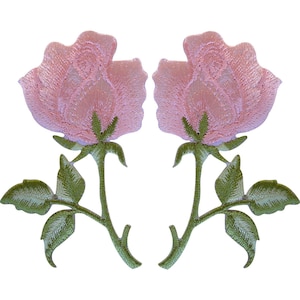 Puede incluir: Dos parches bordados idénticos que presentan una flor de rosa de color rosa claro con un tallo verde y tres hojas verdes. El bordado muestra patrones de puntadas detallados en los pétalos y el follaje, creando una apariencia texturizada.