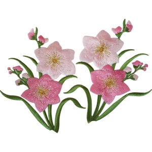 Könnte beinhalten: Zwei gestickte Blumenaufnäher mit hell- und dunkelrosa Blüten und goldgelben Mitten. Jedes Arrangement enthält grüne Stängel und Blätter sowie kleine, geschlossene Blütenknospen, die alle in detaillierter Stickarbeit ausgeführt sind.