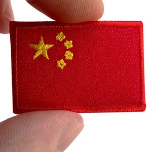 Op de afbeelding: Een rechthoekige geborduurde patch met de vlag van China. De patch heeft een felrode achtergrond met vijf gele geborduurde sterren aan de linkerkant, bestaande uit één grote ster en vier kleinere sterren in een patroon gerangschikt.