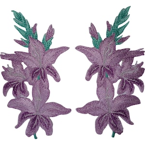 Può includere: Due toppe ricamate simmetriche raffiguranti fiori viola simili a gigli con petali dettagliati, steli e foglie verdi. Il ricamo utilizza diverse tonalità di filo viola per creare profondità e consistenza sugli elementi floreali.