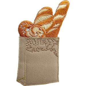 Könnte beinhalten: Ein gestickter Aufnäher, der eine beigefarbene Papiertüte zeigt, gefüllt mit goldbraunem Gebäck, darunter ein Baguette und runde Teilchen. Das Design verwendet detaillierte Stiche, um Textur auf dem Brot und der Tüte zu erzeugen, mit klarem Rand.