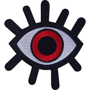 May include: An embroidered patch in the shape of an eye with a black pupil, a bright red iris, and a white sclera. The eye is surrounded by a black border with several radiating black lines extending outward like eyelashes or sun rays.