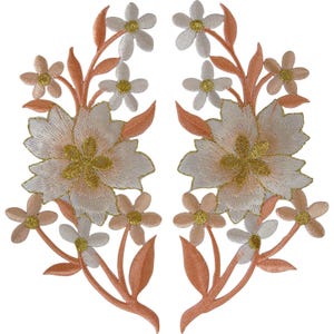 Peut inclure: Deux écussons brodés floraux symétriques présentant de grandes fleurs centrales et des fleurs plus petites tout autour. Le motif utilise du fil blanc et pêche avec des centres et des tiges en or métallique pour un rendu détaillé.